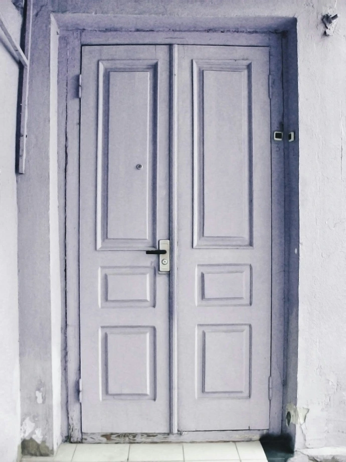 A closed double door with a light purple hue